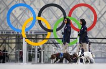  حلقات أولمبية معلقة أمام متحف اللوفر بباريس وسيدتان من الفريق الامني الإماراتي برفقة كلبي حراسة