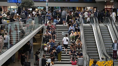 Travellers sit on stairs at the Gare de Montparnasse, at the 2024 Summer Olympics, Friday, July 26, 2024, in Paris, France.