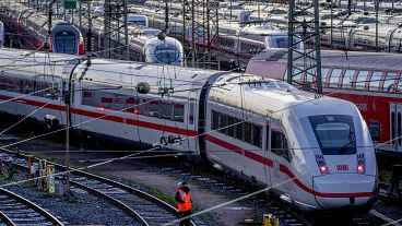 A Deutsche Bahn employee walks past ICE trains that are parked near the central train station in Frankfurt, Germany, Monday, March 27, 2023.