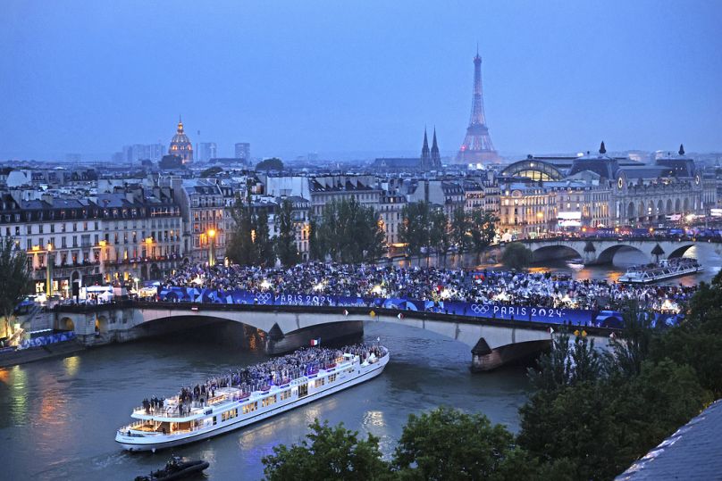 Spectators look on as athletes from Team France cruise on the Seine River during the opening ceremony of the 2024 Summer Olympics, Friday, July 26, 2024 in Paris, France.