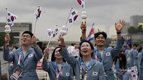 Güney Koreli sporcular Seine Nehri'nden geçerken ülkelerinin bayraklarını dalgalandırıyor, 26 Temmuz 2024