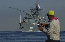 Un pêcheur enroule sa canne à pêche alors que le patrouilleur "Neustrahimiy" arrive pour une "visite de travail" à La Havane, le 27 juillet 2024.