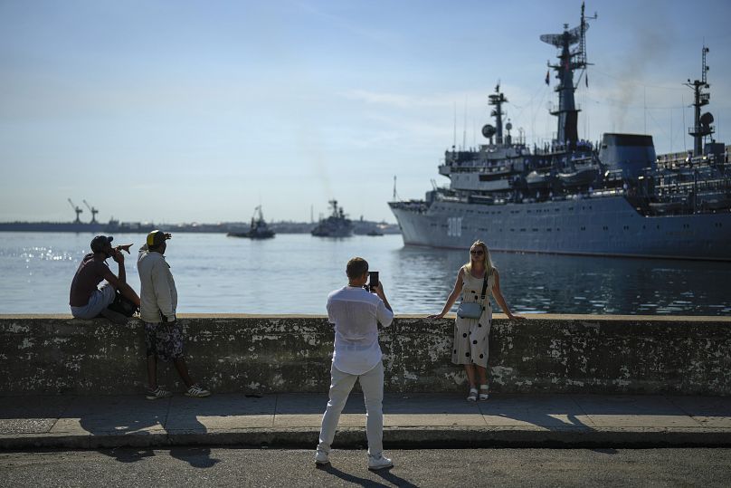 Una mujer posa para una foto con el buque escuela ruso 'Smolnyy' de fondo a su llegada a La Habana, 27 de julio de 2024.