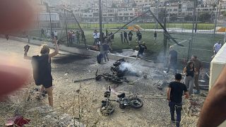 I residenti accorrono per aiutare i bambini feriti dopo che un attacco missilistico ha colpito un campo di calcio a Majdal Shams, nelle Alture del Golan controllate da Israele, 27 luglio 2024.