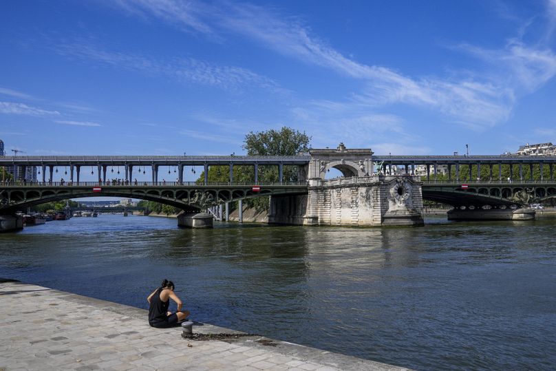 Eine Frau genießt die Morgensonne am Ufer der Seine in Paris.