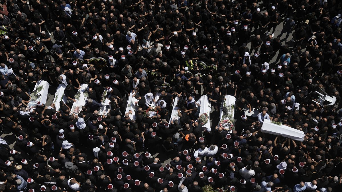 Dolientes de la minoría drusa rodean los cuerpos de algunos de los jóvenes muertos en un ataque con cohetes en los Altos del Golán controlados por Israel, 28 de julio de 2024.