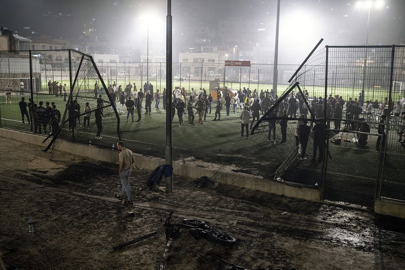 Residents stand at a football field in the Golan Heights that was hit by a rocket on Saturday, July 27, 2024