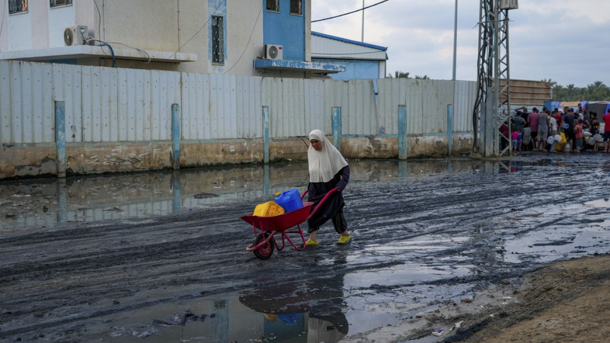 فلسطينيون يتجمعون لملء أباريق المياه بالقرب من إحدى محطات تحلية المياه القليلة العاملة في القطاع في دير البلح بقطاع غزة، 2024- عبد الكريم حنا