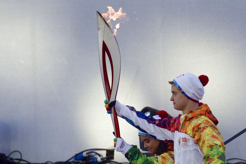 Los jóvenes patinadores artísticos rusos Lina Fedorova y Maxim Moroshkin portan la antorcha olímpica, en la Plaza Roja de Moscú el domingo 6 de octubre de 2013.