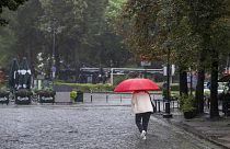 A woman shelters from the rain with an umbrella during a rainy day, in Vilnius, Lithuania, Monday, July 29, 2024.