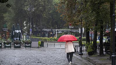 Uma mulher protege-se da chuva com um guarda-chuva durante um dia chuvoso, em Vilnius, Lituânia, segunda-feira, 29 de julho de 2024. 