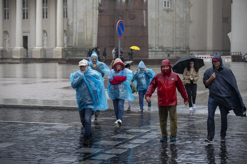 Pessoas atravessam a rua durante o dia de chuva, em Vilnius, Lituânia, segunda-feira, 29 de julho de 2024