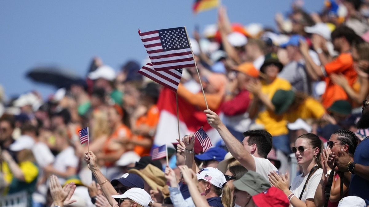 Des supporters de l'équipe des États-Unis regardent les séries du huit d'aviron masculin aux Jeux olympiques d'été de 2024, lundi 29 juillet 2024, à Vaires-sur-Marne, en France. (AP Photo/Lindsey Wasson)