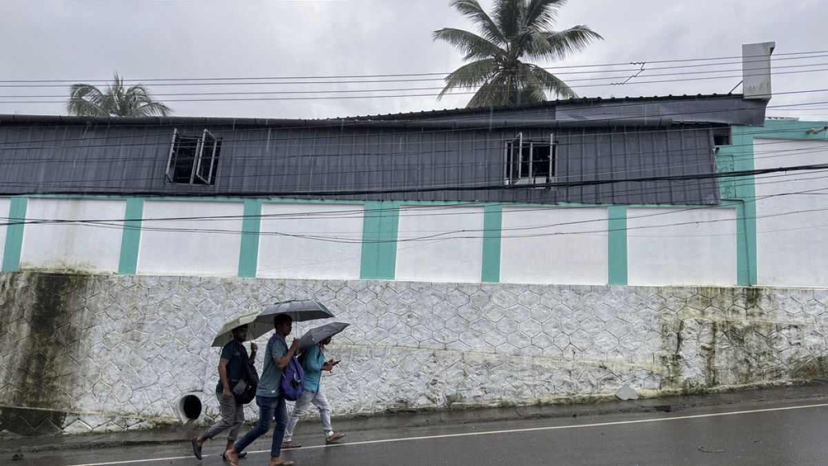 Persone escono al mattino per andare al lavoro tenendo in mano gli ombrelli durante la pioggia a Kochi, nello Stato del Kerala, in India, martedì 30 luglio 2024.