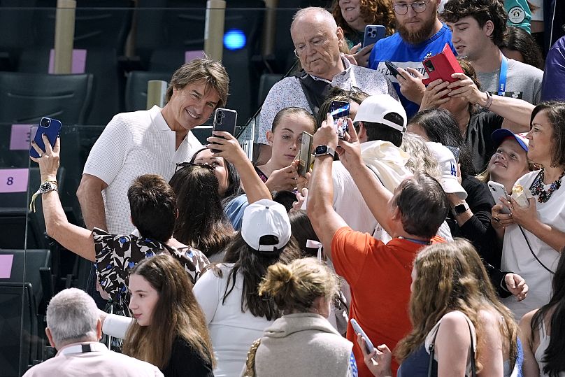 Tom Cruise poses with fans as he attends the women's artistic gymnastics qualification round at the 2024 Summer Olympics