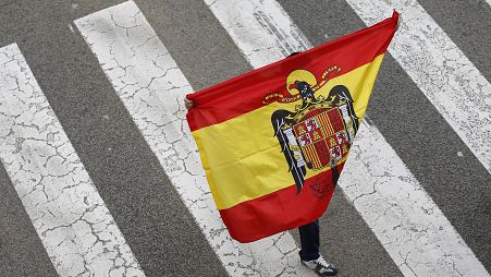 A man holds a pre-constitutional flag during a demonstration for the unity of Spain as they celebrate Spain's Hispanic Day, in Barcelona, Spain, Monday, Oct. 12, 2015.