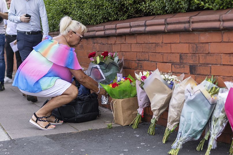 Uma pessoa deixa flores perto do local do crime em Hart Street, Southport