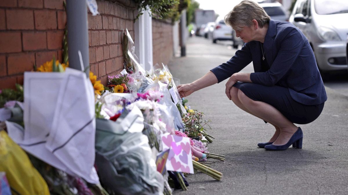 British Home Secretary Yvette Cooper looks at tributes near the scene in Hart Street where two children died and nine were injured in a knife attack.