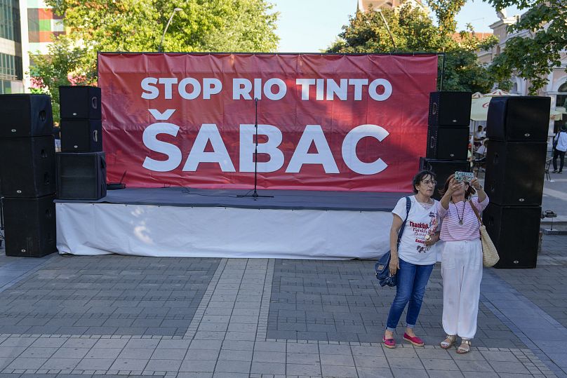 Deux femmes prennent un selfie devant un podium avant une manifestation à Sabac, Serbie, le lundi 29 juillet 2024.