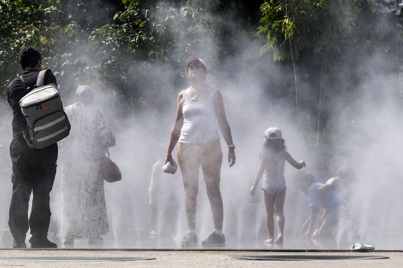 People refresh at a public water mist shower in the center of Paris, France, during the opening ceremony of the 2024 Summer Olympics, Tuesday, July 30, 2024