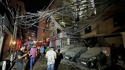 People gather near a destroyed building that was hit by an Israeli airstrike in the southern suburbs of Beirut, Lebanon on Tuesday