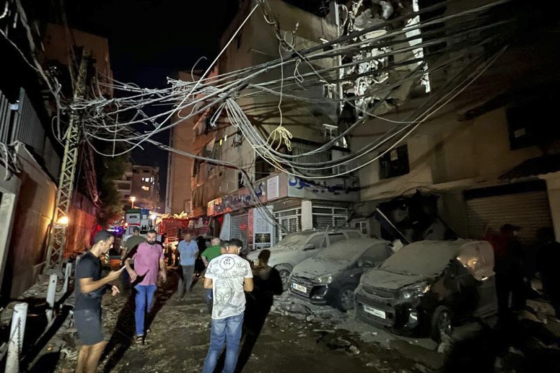 People gather near a destroyed building that was hit by an Israeli airstrike in the southern suburbs of Beirut, Lebanon, Tuesday, July 30, 2024.