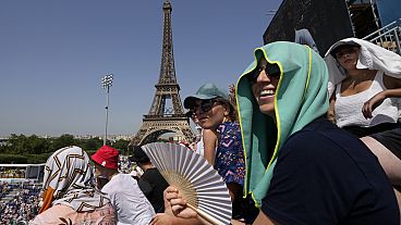 Spectator uses a fan to keep cool in the sweltering heat at the 2024 Summer Olympics, July 30, 2024, in Paris, France. (AP Photo/Robert F. Bukaty)