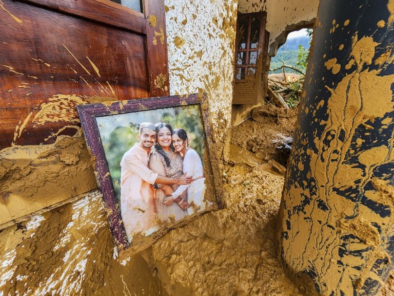 A framed photograph lies partially covered in mud at a damaged house after landslides hit hilly villages in Wayanad district, Kerala state, India, Tuesday, July 30, 2024.