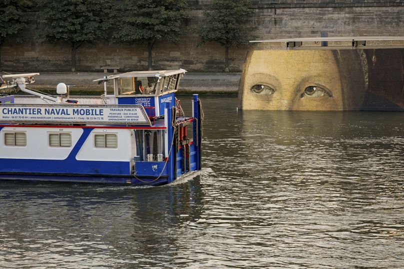 A ship sails past reproductions of artworks decorating the banks of the River Seineat the 2024 Summer Olympics on Tuesday