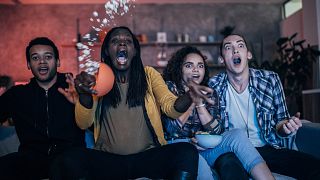 A group of young people watch TV