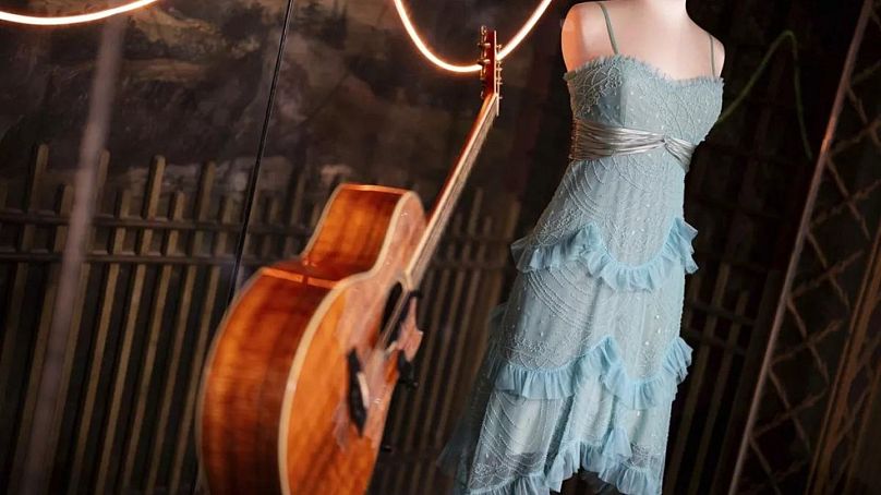 A guitar and stage costume from previous concert tours are displayed at the 'Taylor Swift Songbook Trail Exhibition' at the Victoria & Albert Museum.