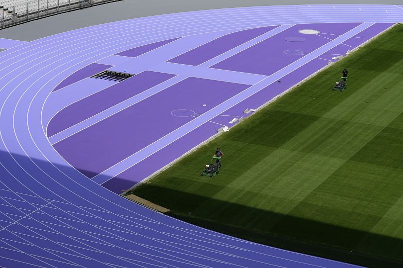 Trabajadores siegan el campo mientras continúan los preparativos en el Stade de France de cara a los Juegos Olímpicos de París, el martes 7 de mayo de 2024, en París.