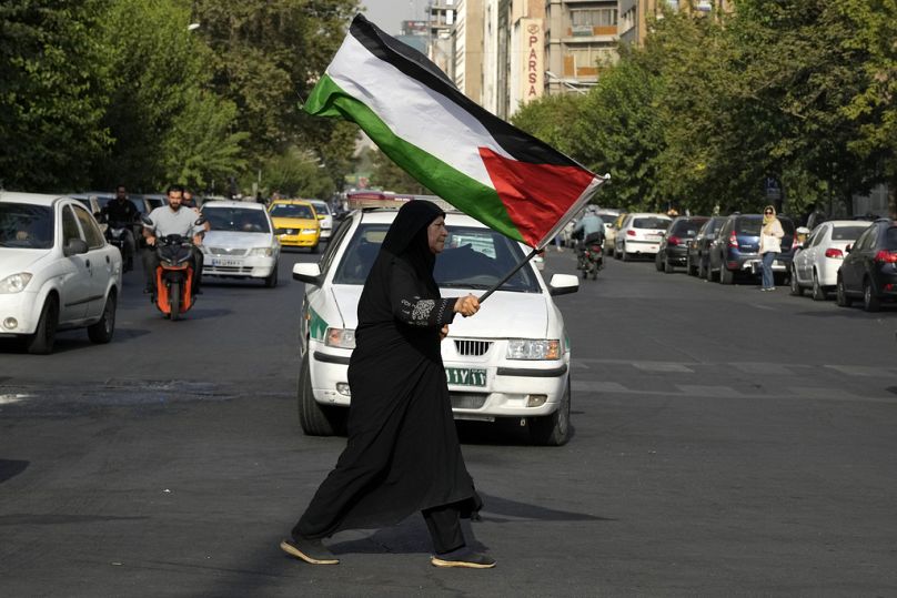 An Iranian woman carries a Palestinian flag to condemn the killing of Hamas leader Ismail Haniyeh, at Felestin (Palestine) Sq. in Tehran, Iran, Wednesday, July 31, 2024. 