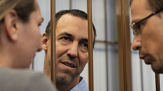 French citizen Laurent Vinatier speaks with his lawyers from a cage in a courtroom in the Zamoskvoretsky District Court in Moscow, Russia, Wednesday, July 31, 2024.