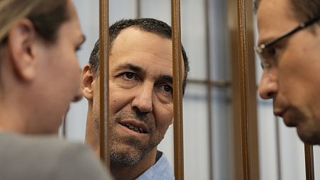 French citizen Laurent Vinatier speaks with his lawyers from a cage in a courtroom in the Zamoskvoretsky District Court in Moscow, Russia, Wednesday, July 31, 2024.