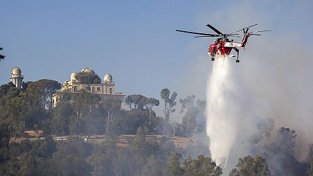 A helicopter drops water over a fire in Monte Mario, behind Piazzale Clodio in Rome, 31 July 2024
