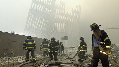Nesta fotografia de arquivo de 11 de setembro de 2001, os bombeiros trabalham por baixo dos pilares destruídos do WTC.