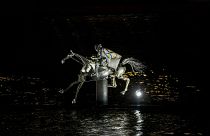 A performer on a mechanical horse carries the Olympic flag down the river Seine in Paris, France, during the opening ceremony of the 2024 Summer Olympics, July 26, 2024.