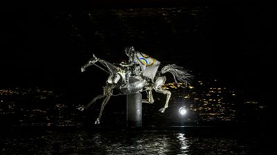 A performer on a mechanical horse carries the Olympic flag down the river Seine in Paris, France, during the opening ceremony of the 2024 Summer Olympics, July 26, 2024.