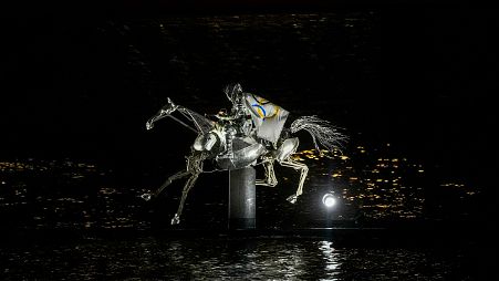 A performer on a mechanical horse carries the Olympic flag down the river Seine in Paris, France, during the opening ceremony of the 2024 Summer Olympics, July 26, 2024.