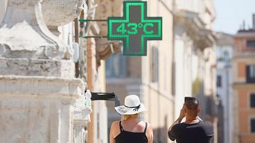 A man takes a photo of the temperature of 43 degrees C recorded in the sun outside a pharmacy in Rome, 11 July 2024. 