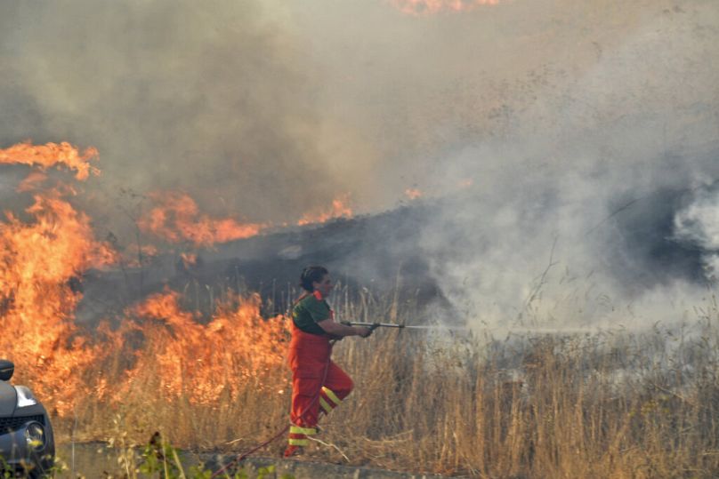 Una volontaria cerca di spegnere un incendio