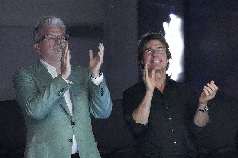 Tom Cruise, à direita, e o realizador de Missão Impossível, Christopher McQuarrie, assistem à natação durante os Jogos Olímpicos de verão de 2024 - Sábado, 27 de julho de 2024