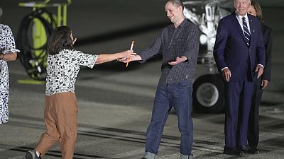 O repórter Evan Gershkovich é recebido na pista pela sua mãe, Ella Milman, enquanto o Presidente Joe Biden e Kamala Harris o observam na Base da Força Aérea de Andrews.