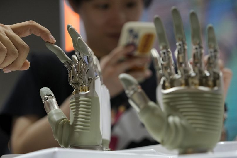 A visitor touches a humanoid robot hand on display at an AI exhibition booth in Shanghai, 4 July 2024