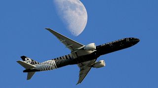 An Air New Zealand passenger plane flies past the moon on its way to the Los Angeles International Airport from London, August 2015.