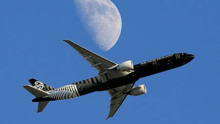An Air New Zealand passenger plane flies past the moon on its way to the Los Angeles International Airport from London, August 2015.