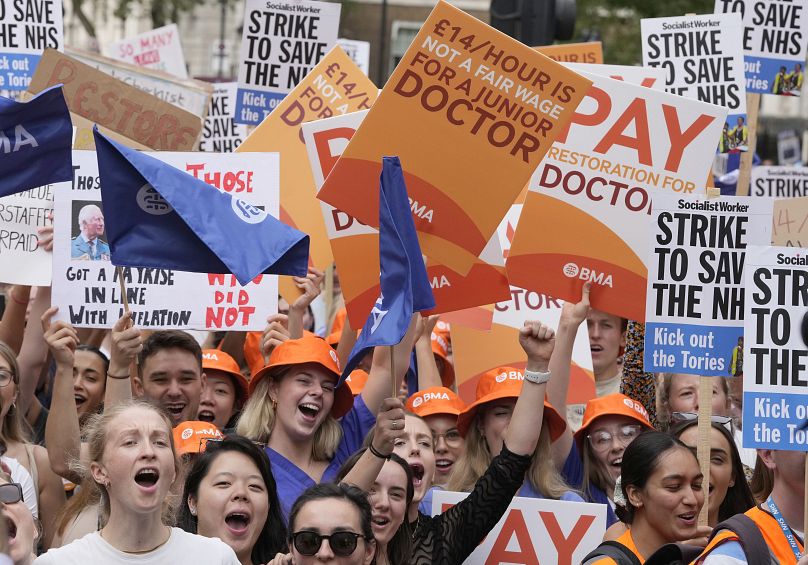 Demonstrators hold banners during a junior doctors rally outside Downing Street in London, Friday, August 11, 2023.