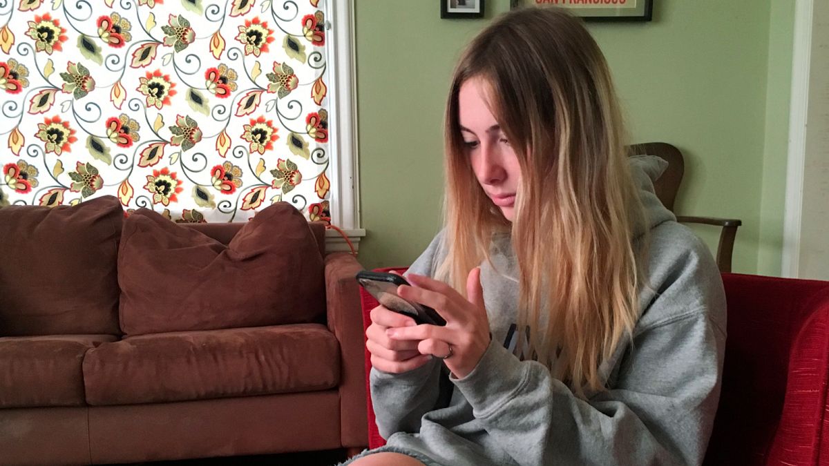 Una estudiante con su teléfono en la mano.