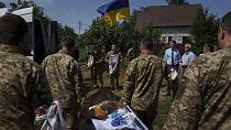 A guard of honour carry the coffin of their comrade in the village of Putrivka, Ukraine, Thursday, Aug. 1, 2024. (AP Photo/Evgeniy Maloletka)